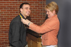Barb Fishback places the Honors College medallion on Aaron Sattler at an Honors  College ceremony in May. Sattler graduated in May with Honors College Distinction and  a degree in Spanish.