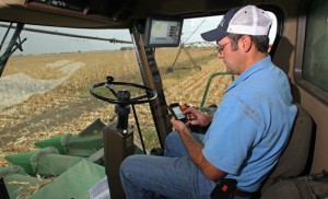 Keith Alverson â€™02 uses his iPhone to check the iGrow website in the cab of his computer-equipped tractor last fall.