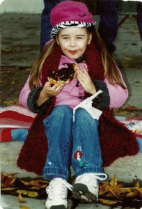 Terry Woster's granddaughter, Lara Widman, sits on the curb in front ofÂ Fergen's working through aÂ chocolate-covered doughnut at Hobo Day 1999. Watching the parade from Fergen's Main Avenue location was a Woster tradition for years.