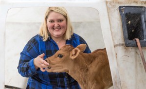 Brittany Moorse poses with a calf in a calf hutch.