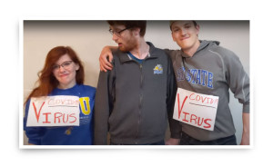 Three students, two wearing virus signs, create a video about COVID-19.