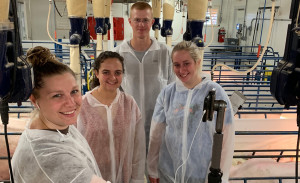 Four students take a selfie photo in a hog barn.