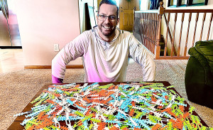 A man sits with colorful 3D-printed strips.