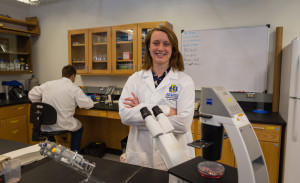 A female scientist stands in a lab.