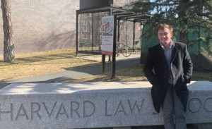 A man poses next to a Harvard Law sign
