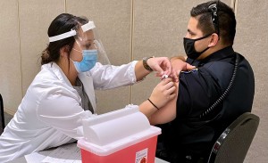 A student pharmacist gives a police officer a vaccination.