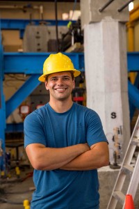 Student stands with arms crossed wearing a hard hat.