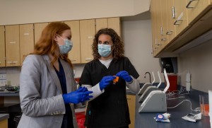 Two women use a machine to test for COVID-19.