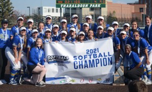 Softball team poses with a trophy and championship banner.