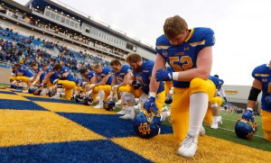 Football players kneel in the endzone for a quiet moment before starting the game.