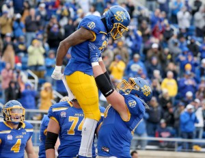 A football player lifts up another player in celebration.