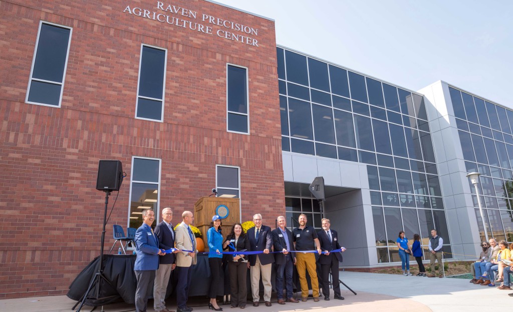 Several people pause for a photo before cutting the ribbon and opening the new building.