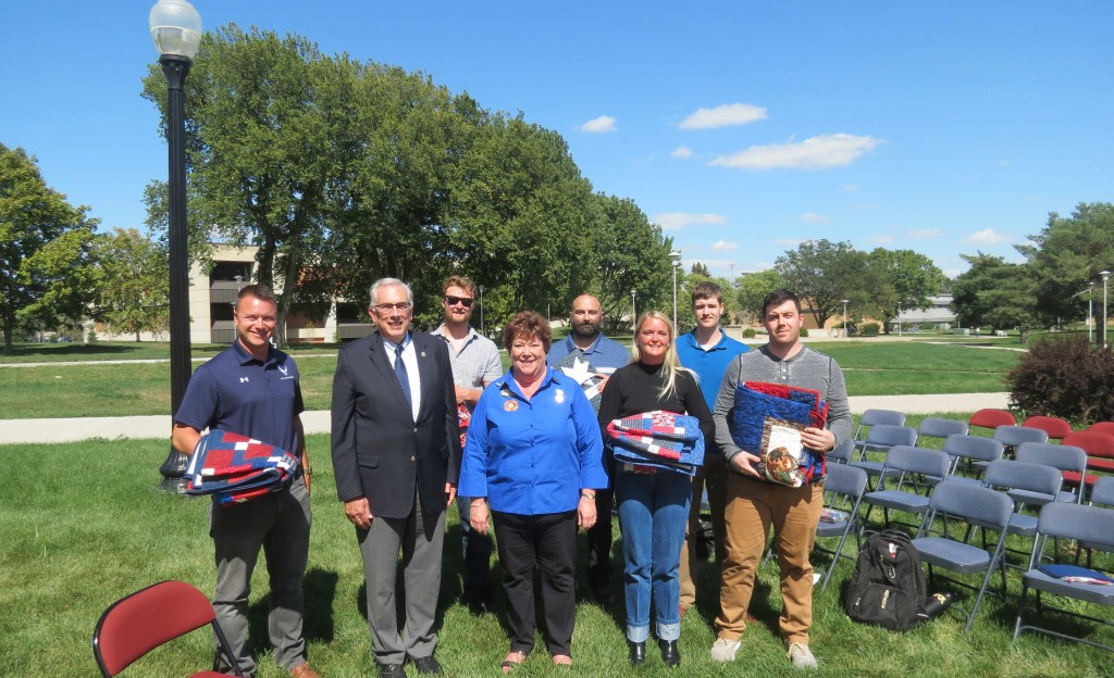 six military veterans hold quilts they were honored with. 
