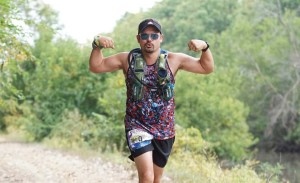 A man flexes for the camera while running in a 100-mile race.