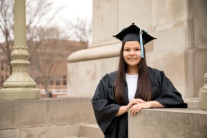 A female college student poses in her graduation cap and gown.