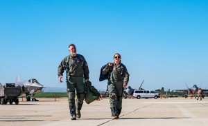 A female fighter pilot escorts a visitor to a plane.