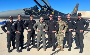 The F-16 Viper Demo Team, lead by a female pilot, pose in front of an F-16. 