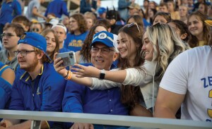 University president takes a selfie with students during an SDSU football game.