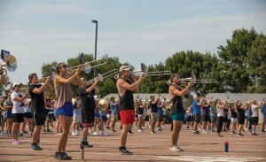 A group of students play trombone during marching band rehearsal.