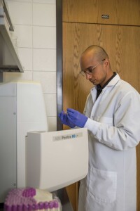 A scientist takes a test tube out of a machine.