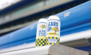 Two Ears Up beer cans sitting on a bleacher seat.