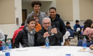 The president of the university takes a selfie with four middle schoolers.