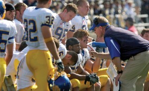 A football coach wags his finger while talking to his players.