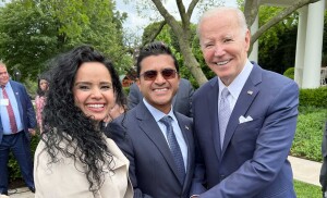 A man and woman stand smiling with the president of the united states. 
