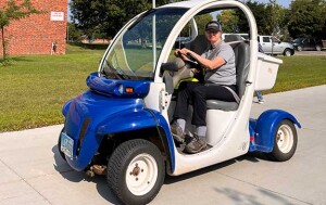 A woman drives an electric golf cart.