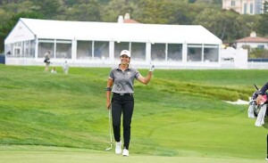 A woman waves on the golf course.