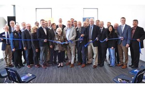 A group of people cut a blue ribbon to officially open the Poet Bioproducts Center.