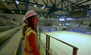 A woman wearing a hard hat overlooks a construction project.